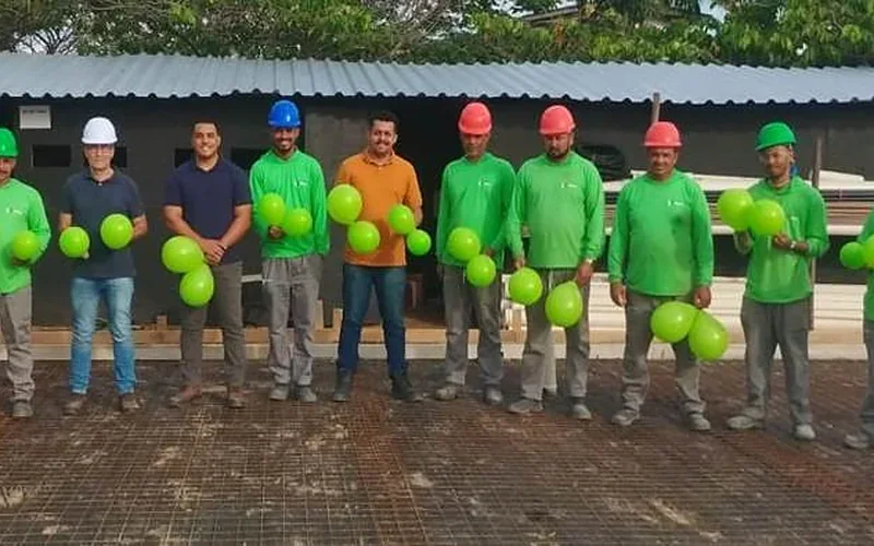Equipe com uniformes, capacetes e EPIs em frente a uma obra