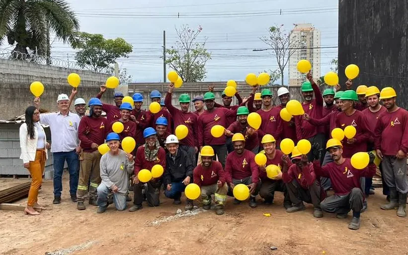 Equipe de obra com capacetes reunida em campanha de saúde e segurança